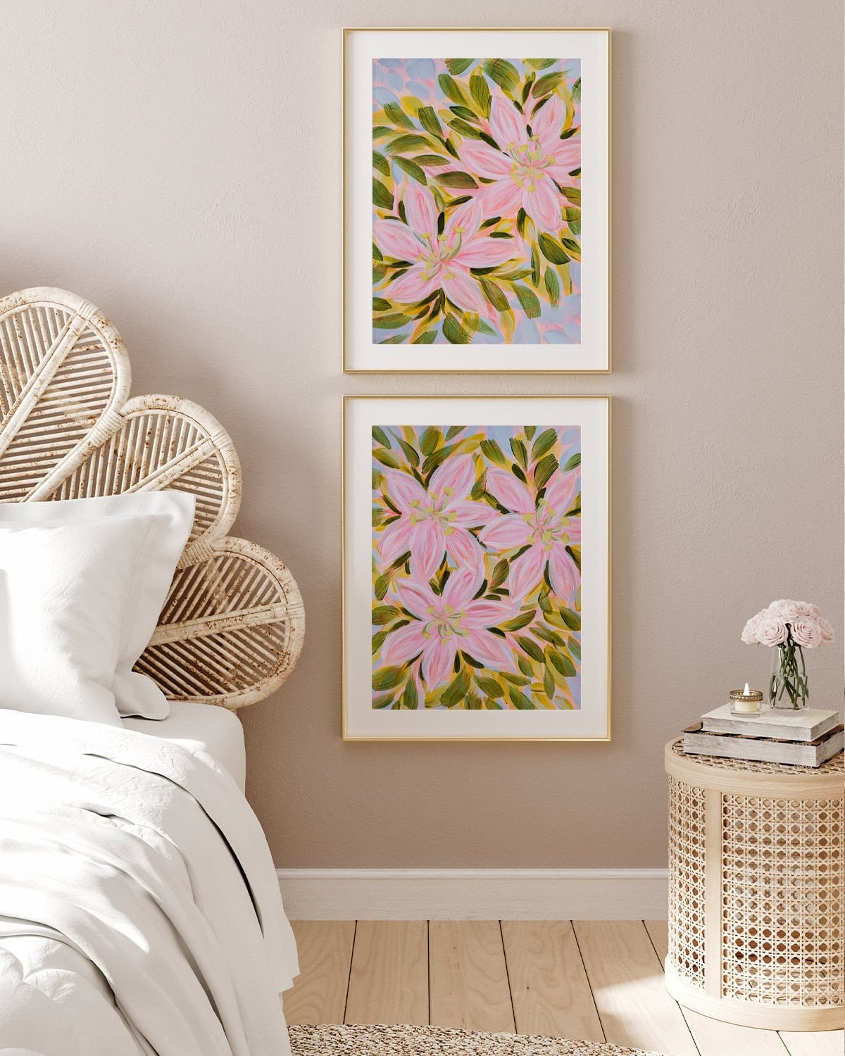 2 framed pink lily paintings by Bonnie Sorsby stacked vertically on the wall beside a rattan headboard, over a woven nightstand