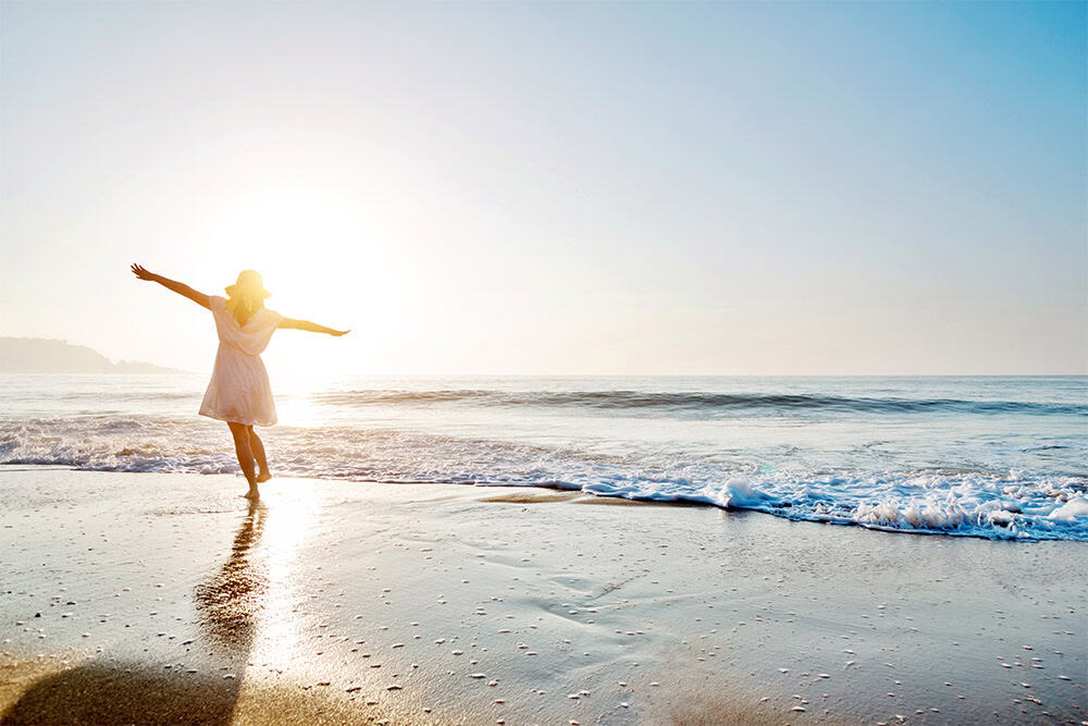 woman dances on the beach as she discovers her most aligned marketing style and thrives in her entrepreneurial adventure with clarity and a beautiful brand presence that truly reflects her essence