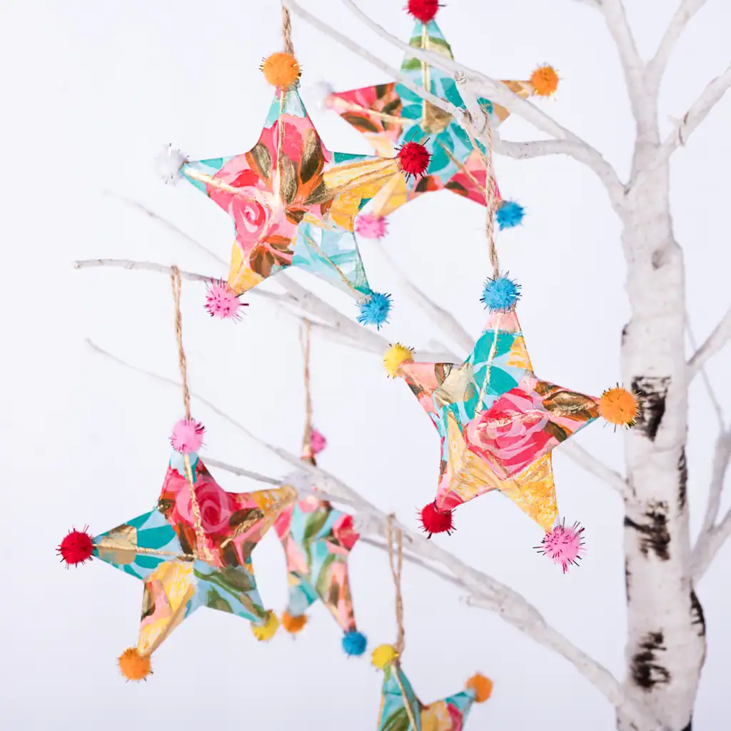 Whimsical handmade floral star ornaments with pom pom details, artisan holiday decorations in vibrant colors.