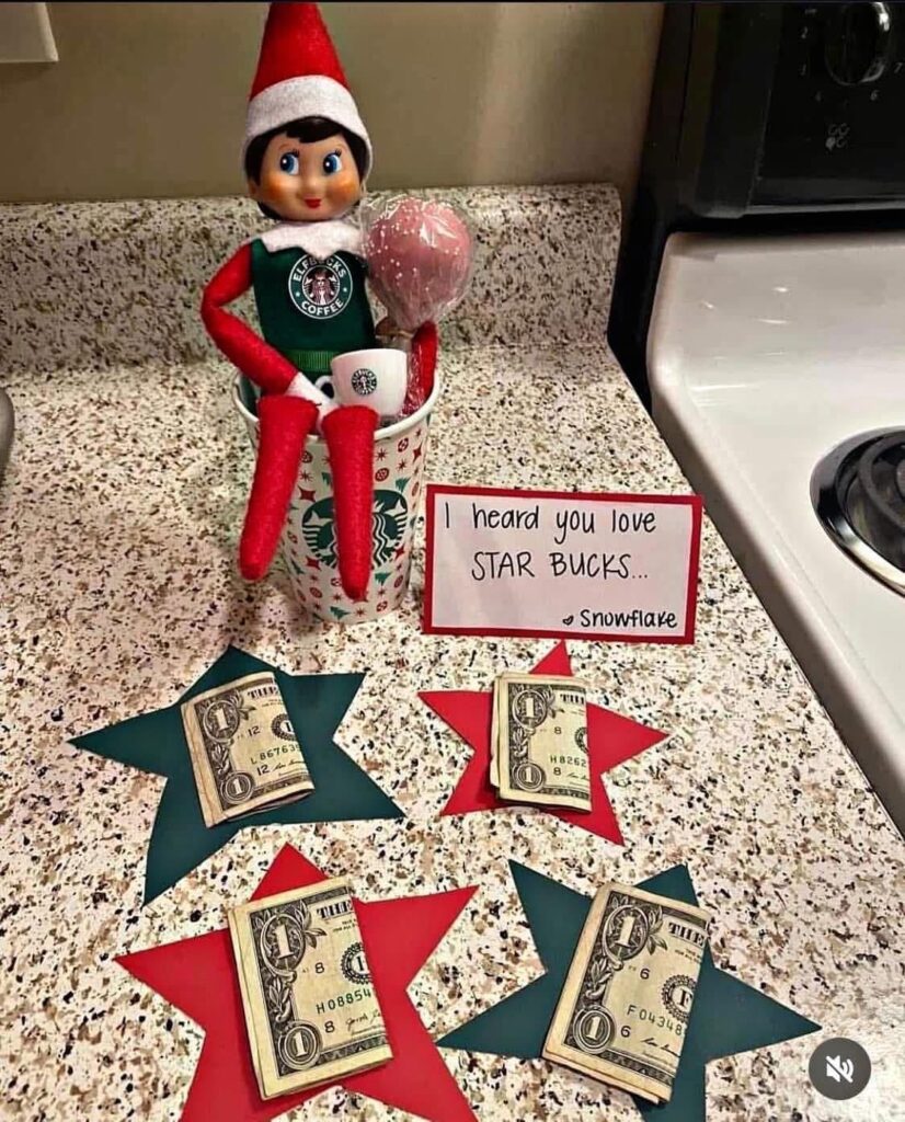 Elf on the Shelf sitting in a Starbucks cup with dollar bills on star cutouts. Easy elf idea for a fun morning surprise.