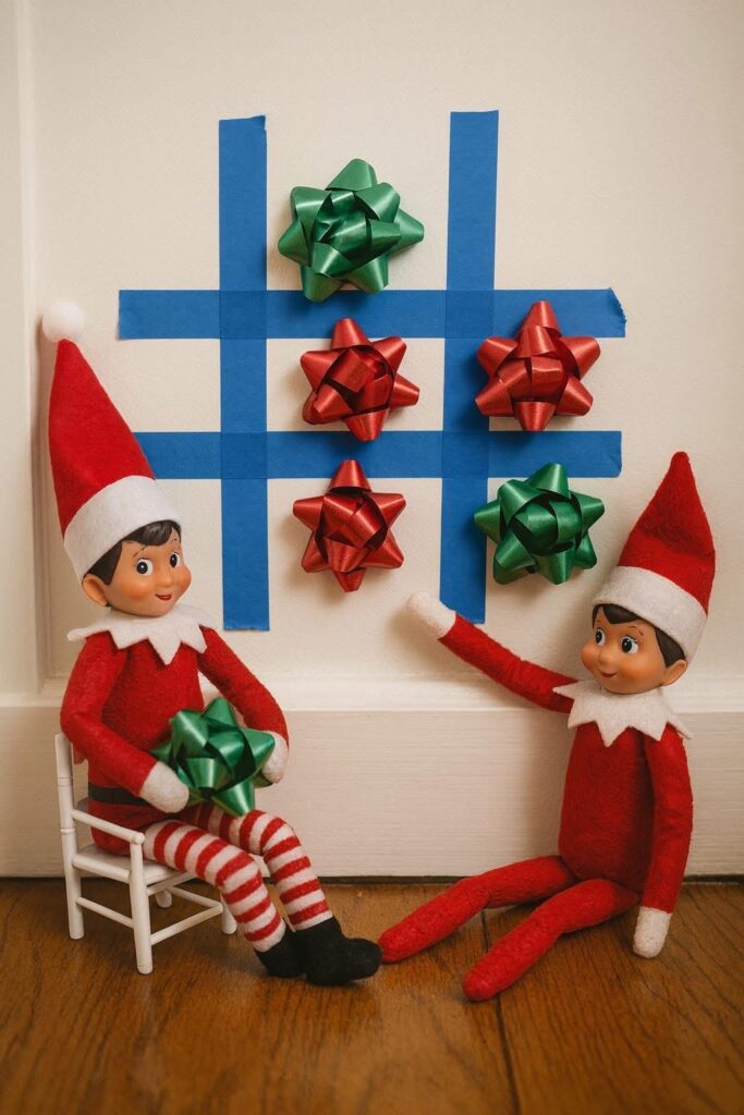 Two elves playing tic-tac-toe using gift bows and painter’s tape on the wall. Easy holiday elf activity.