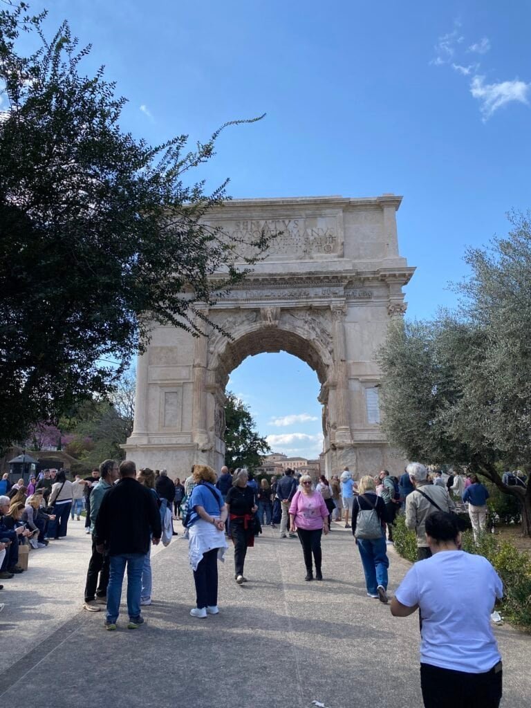 Ancient Roman arch surrounded by visitors at a popular Italian landmark, showcasing Italy's rich history and architecture.