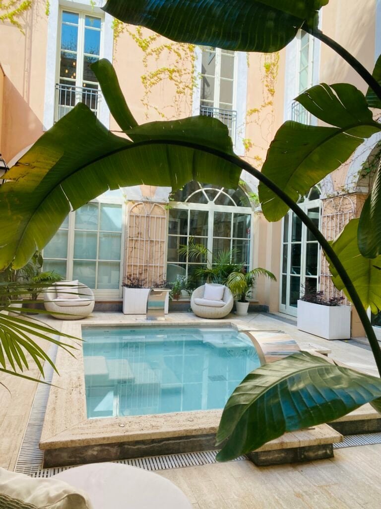 A serene indoor pool area surrounded by lush tropical foliage and stylish seating, creating a tranquil retreat perfect for relaxation and artistic inspiration.