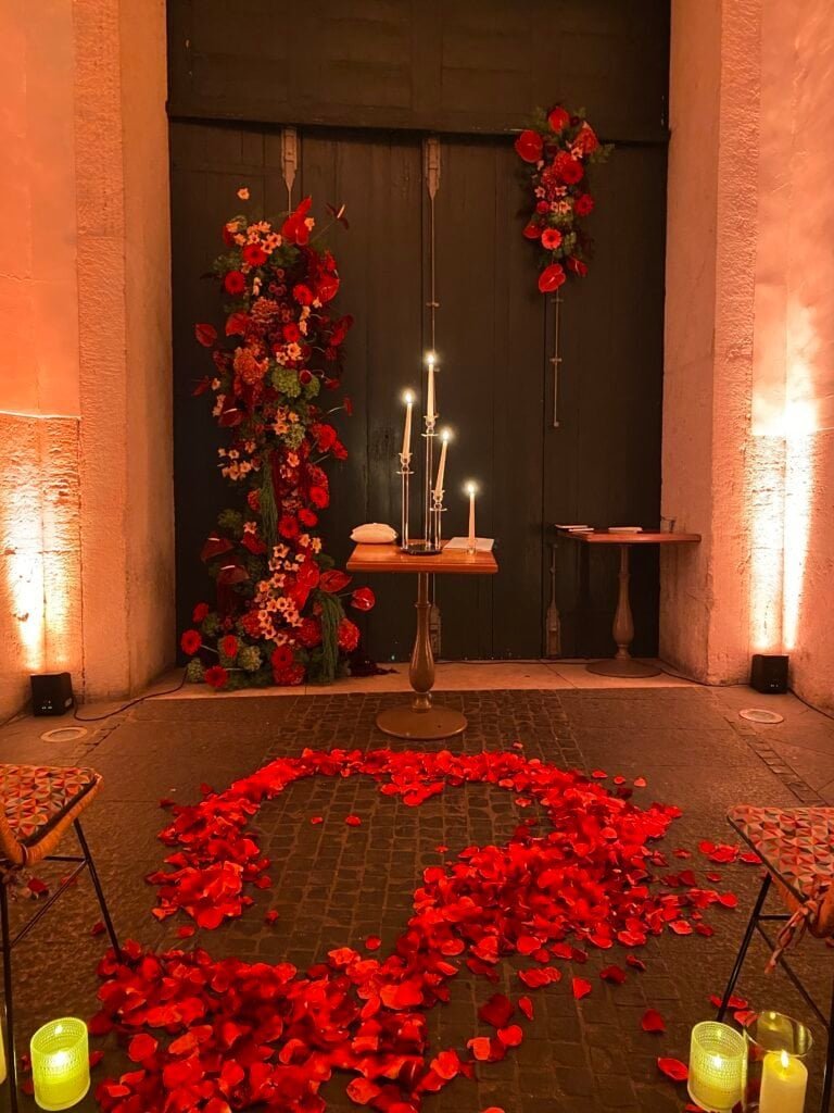 Elegant wedding altar with red roses, candles, and rose petal heart on the floor, creating a romantic atmosphere for a special ceremony.