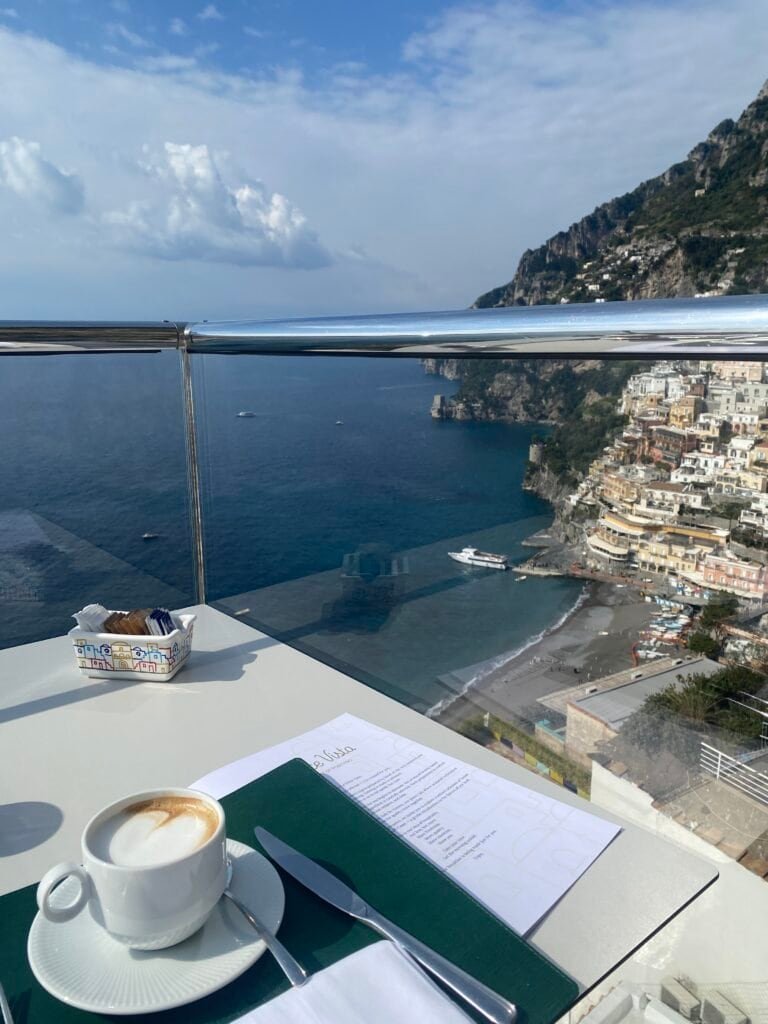 Amalfi Coast coastline with colorful buildings, cliffs, and the sea, captured from a balcony during daytime.