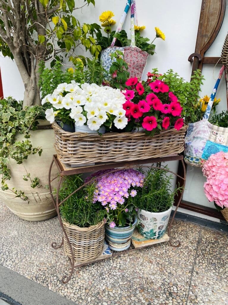 Vibrant pink, white, and yellow flowers arranged on a rustic garden cart outdoors.