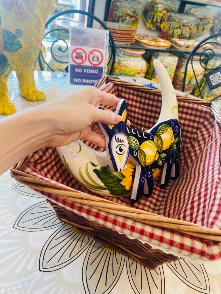 Hand holding a ceramic cat sculpture with detailed painted features and vibrant colors.