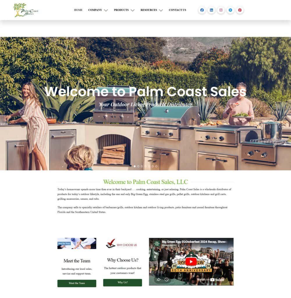 Outdoor kitchen with stainless steel appliances and countertops in a lush garden setting.