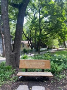 Wooden park bench with Northford Park engraved, surrounded by lush green trees and garden in Asheville, North Carolina.