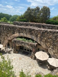 Stone archway with outdoor seating and umbrellas in a lush green setting in Asheville, North Carolina.
