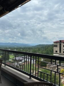 Scenic view from a balcony overlooking Asheville, North Carolina, with mountains, trees, and a cloudy sky.