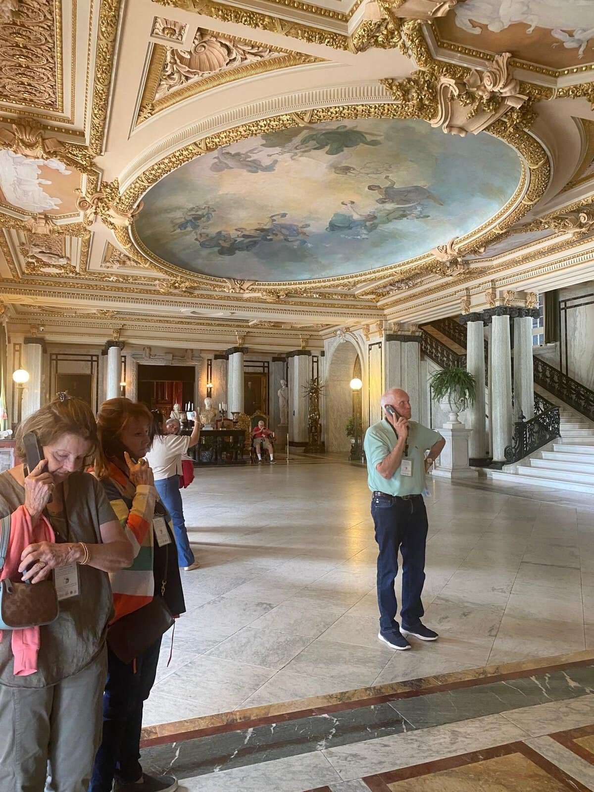 visitors in the grand marble hall with a painted ceiling at the Flagler Museum
